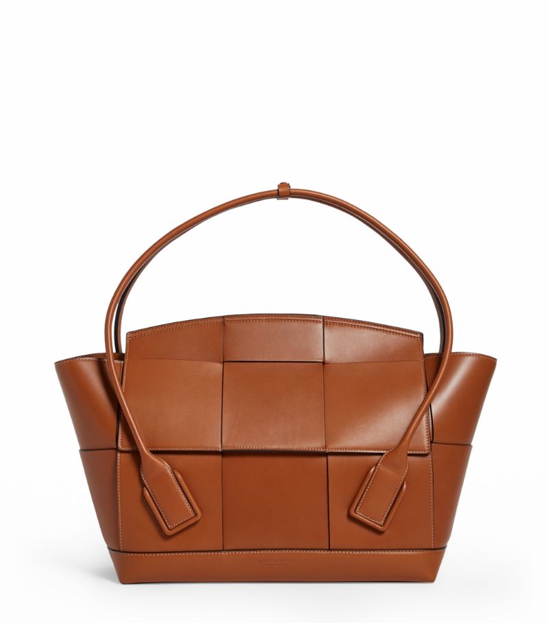 Adorned with an oversized Intrecciato weave, the Arco 56 bag boasts a large arc-shaped silhouette with twin top handles. Showcasing the label's Italian craftsmanship, the large flap closure lifts to reveal a spacious suede interior featuring two slip pockets and a zipped compartment.