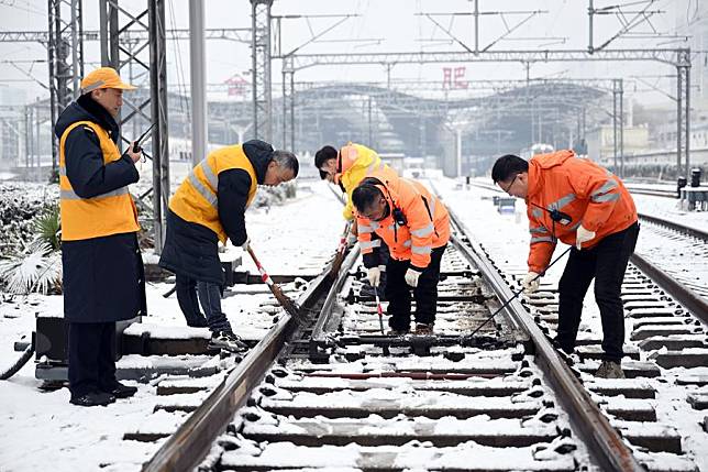 Staff members remove snow on a railway in Hefei, east China's Anhui Province, Feb. 4, 2024. (Xinhua/Zhou Mu)