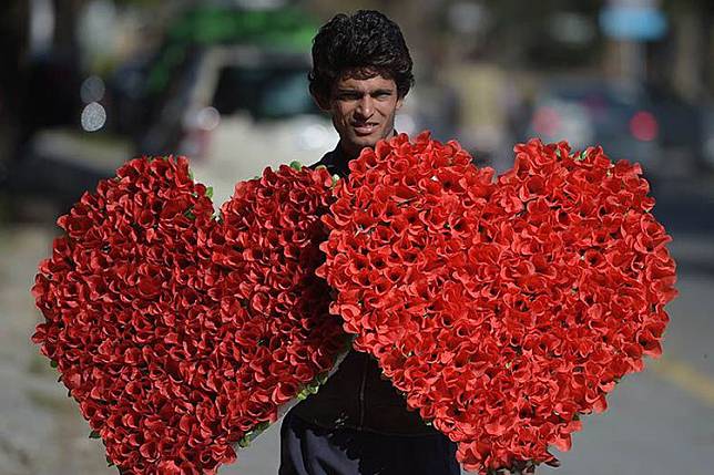 Seorang pedagang membawa buket bunga berbentuk hati yang dijual menjelang perayaan hari Valentine di jalanan kota Islamabad, Pakistan. Pemerintah Pakistan telah melarang perayaan hari kasih sayang tersebut sejak 2017 lalu.(Aamir Qureshi / AFP)