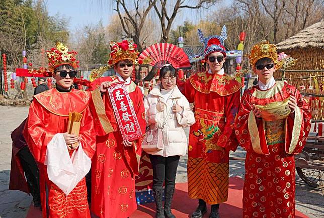 A tourist poses for photos with staff members dressed as “Caishen”, or the “God of Wealth”, at a temple fair in Yinan County, Linyi City, east China's Shandong Province, Feb. 13, 2024. (Photo by Wang Yanbing/Xinhua)