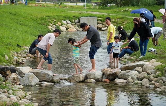 新北市新店親情河濱公園新打造仿自然景觀的人工溪流今天（廿六日）正式開放，附近大人小孩已搶先玩的不亦樂乎。 （記者吳瀛洲攝）