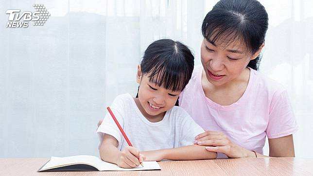 大陸1名8歲女童寫功課不專心，邊寫邊看卡通。(示意圖／TVBS)