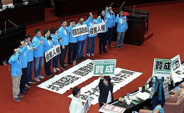 立法院31日院會三讀通過「反滲透法」草案，國民黨立委在議場內舉起標語，抗議此案侵害人權、侵害言論自由。（姚志平攝）