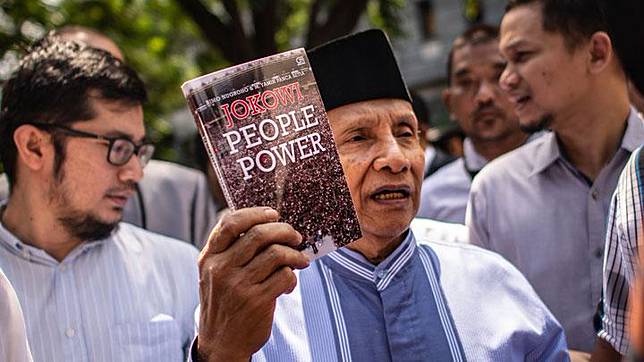 Ketua Dewan Kehormatan PAN Amien Rais menunjukkan buku berjudul Jokowi People Power saat jeda pemeriksaan untuk salat Jumat, di Polda Metro Jaya untuk memenuhi panggilan, Jakarta, 24 Mei 2019. ANTARA