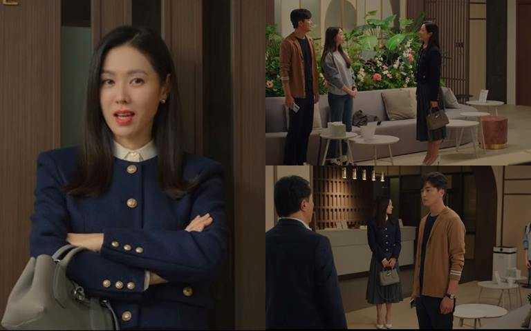 孫藝珍選擇溫柔沉穩的斑鳩灰Roseau手提包配搭一身內斂大器的深藍色系套裝。(圖／翻攝Netflix)