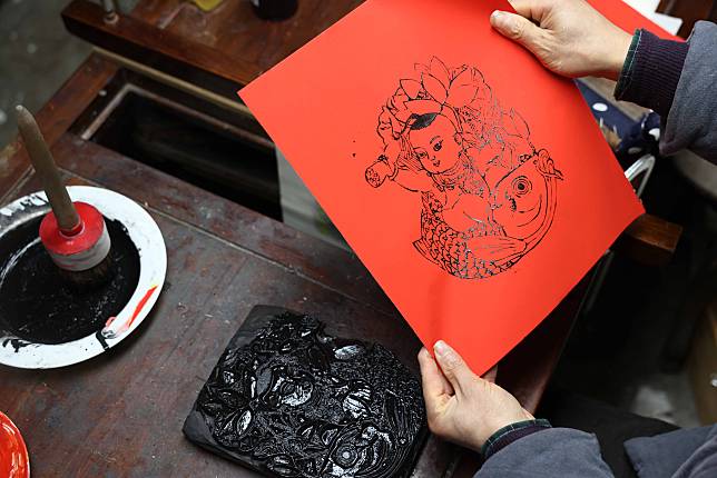 Tong Min looks at a copy of woodcut New Year painting at a studio in Hefei, east China's Anhui Province, Feb. 4, 2024. (Photo by Xie Chen/Xinhua)