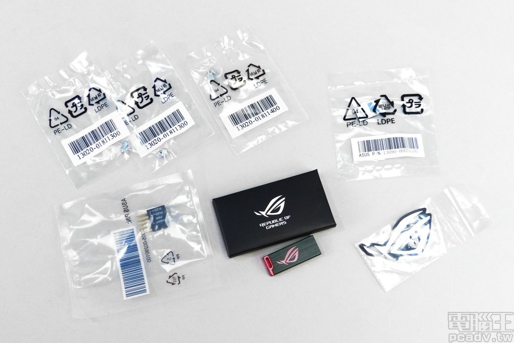 小零件包含 4 組 M.2 螺柱與螺帽、單面上料 M.2 SSD 所使用的橡膠墊片，Q-Connector、金屬 ROG 眼型標誌銘牌貼紙，以及內含公用程式與驅動程式的 USB 隨身碟