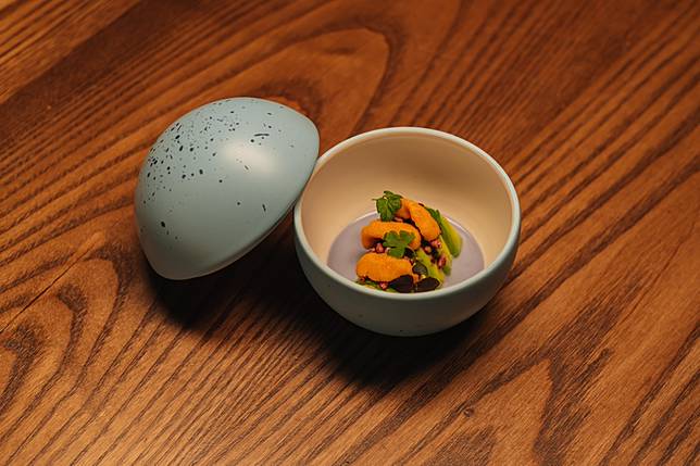 《Gaia 大地》系列亮點食器「藍鵲蛋」盛裝蟹肉、酪梨、海膽、越南香菜，用蝶豆花將融入大量越南香菜的椰奶湯汁染成藍色，呼應器皿色彩與餐廳取名的發想意念，開啟用餐體驗的序章。（Photo Credit：台灣設計研究院）
