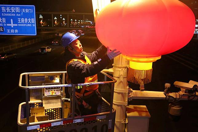 A worker adjusts a red lantern on Chang'an Avenue in Beijing, capital of China, Feb. 1, 2024. (Photo by Zhang Chao/Xinhua)