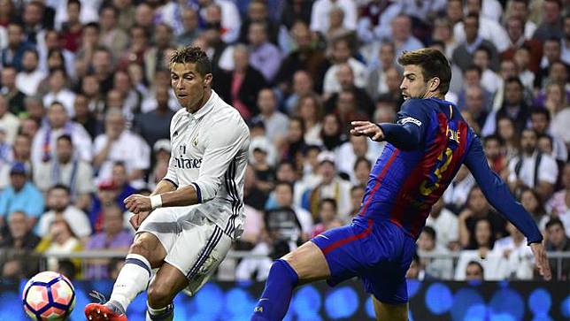 Salah satu upaya bek Barcelona, Gerard Pique untuk menghentikan pergerakan penyerang Real Madrid, Cristiano Ronaldo. (GERARD JULIEN / AFP)