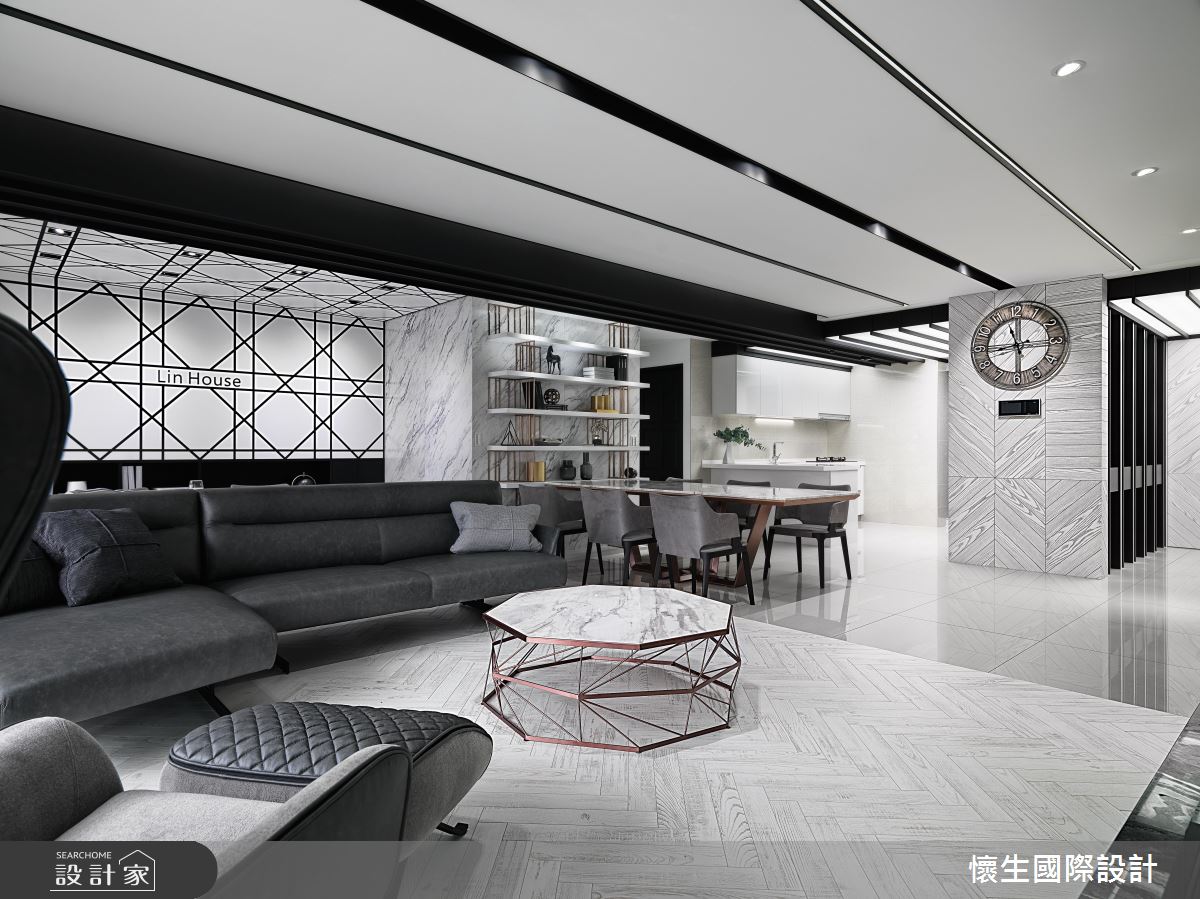 客廳地板以大理石紋路的長形花磚交錯斜貼，與一旁的餐廳與主動線做出空間區隔，牆面或柱面也多運用了大理石紋理做表面處理，黑白配色給人時尚前衛中又帶有些經典的感受。