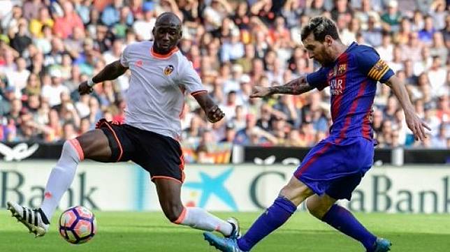 Pemain Valencia Eliaquim Mangala mencoba menghentikan pemain Barcelona Lionel Messi dalam pertandingan La Liga musim 2017/18. [AFP]