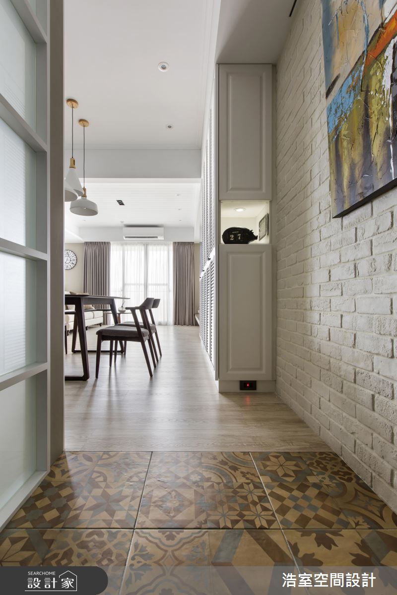 同樣在玄關進入客廳的廊道地板室使用大塊的花磚，拼接客廳的木質地板，使用材質做出空間區隔，花磚與木質地板、文化石牆面互相呼應搭配，展現美式風格。
