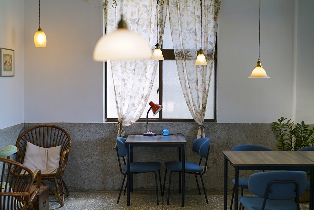 室內空間維持昔日台鐵人員值班室的樣貌，餐桌上點綴舊式檯燈和小豬存錢圖，勾動六、七年級生的兒時回憶。(攝影/Cindy Lee)