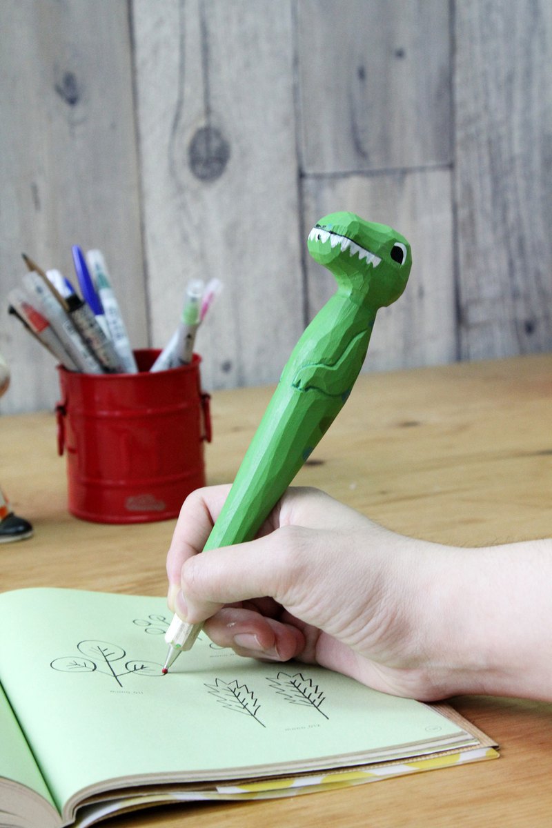 恐龍是許多人的最愛! 這款英國設計的恐龍造型原子筆相當可愛，圓圓的大眼睛，搭配浮雕的雙手，讓人愛不釋手! 木頭手感厚實，手工立體雕刻，水性塗料上色，有著濃厚的質樸感，19公分的長度，不管放在筆筒或桌上