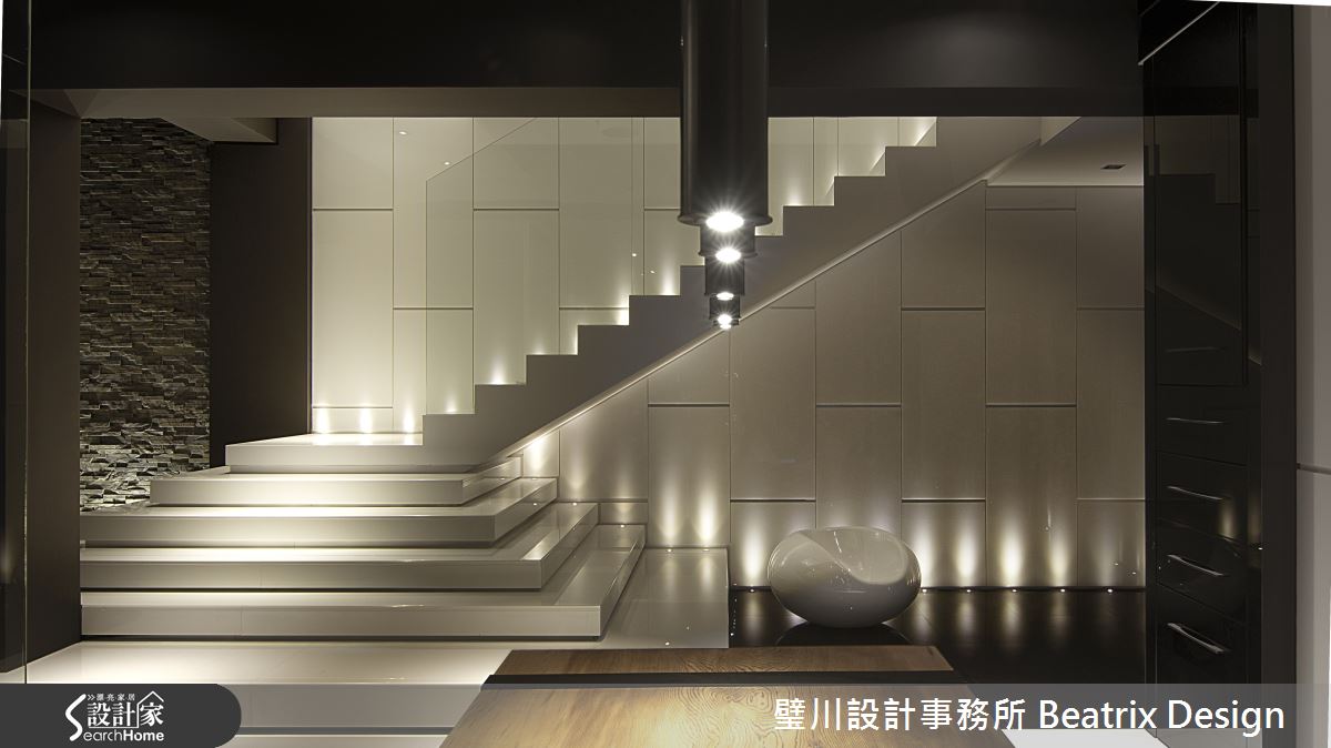 在上樓梯的前五階作一個小轉折，減緩樓梯坡度，空間的線條感受也大不相同，全玻璃的扶手兼顧安全性與視覺穿透性考量，燈光則兼具了照明與空間氛圍的營造。