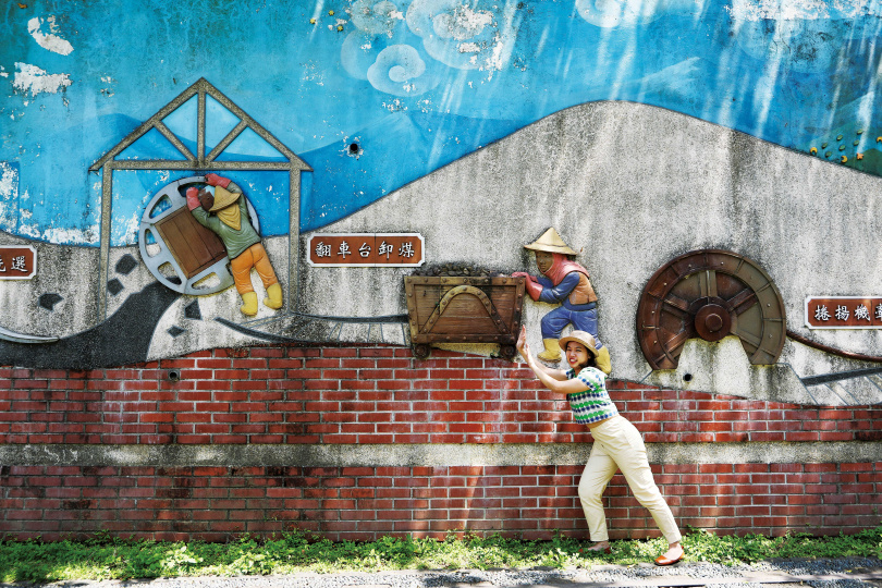 「和興炭坑」園區有一面陶板彩繪壁畫《煤的一生》，不但具有教育意義，遊客也能在此拍出逗趣照片。（圖／于魯光攝）