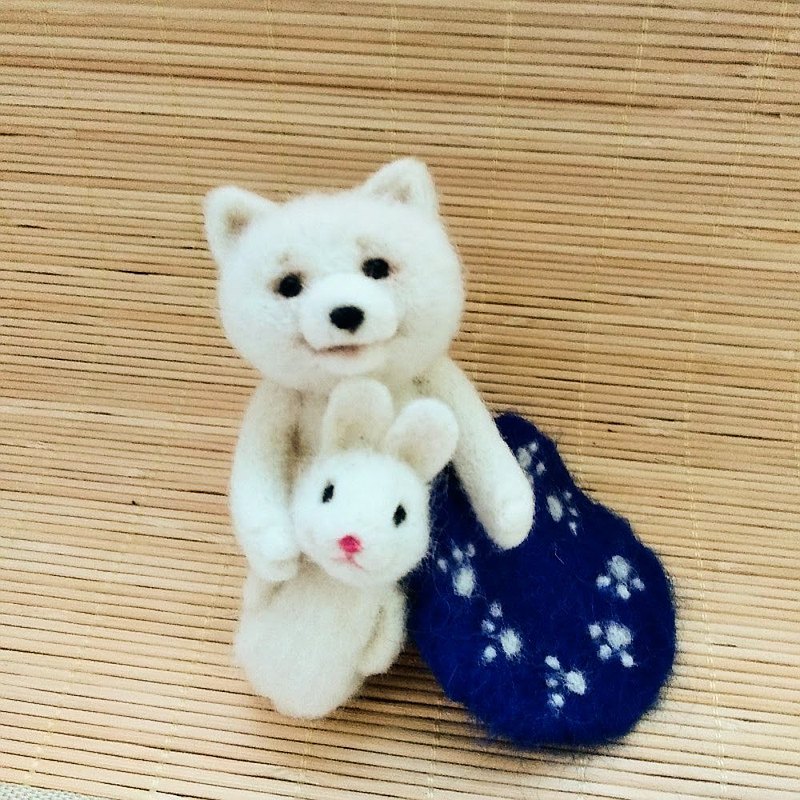 毛氈玩具薩摩耶狗。可愛的小狗帶著兔子玩具。
