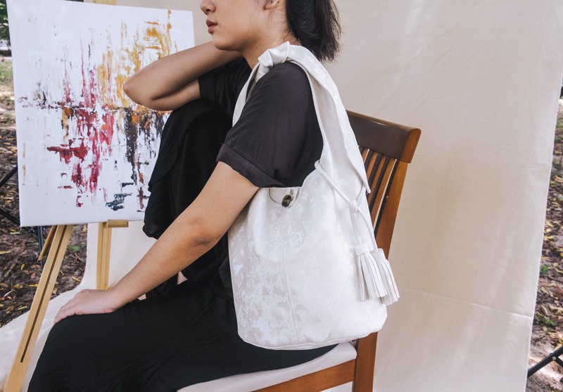 這款自綁式流浪漢包飾有流蘇裝飾。