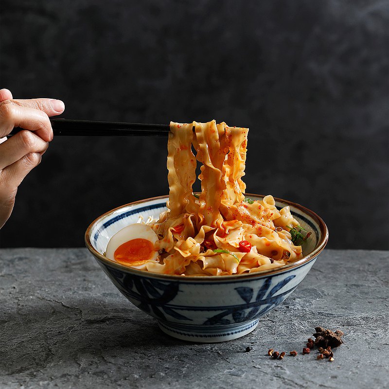 手工日曬波浪寬麵，僅用良好水質、鹽及嚴選麵粉天然製作，Q彈有咬勁，滑順細緻；以純釀醬油、花椒、八角為基底，添加多種自然辛香料，堆疊出濃郁香氣與層次口感，醇厚滋味不油不膩。