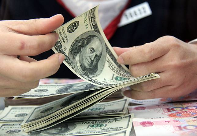 A worker counts the U.S. dollars at a bank in Tancheng County of Linyi City, east China's Shandong Province. (Xinhua/Zhang Chunlei)