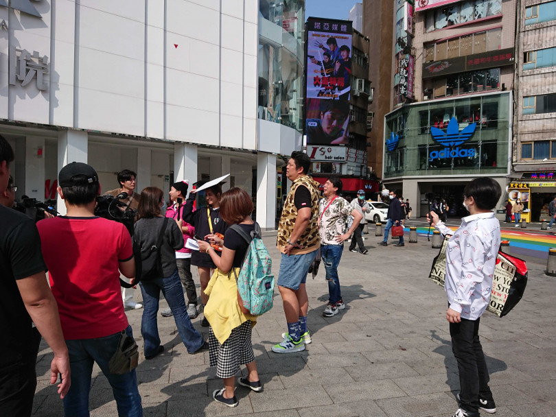 天氣炎熱，莎莎忍不住將節目道具版拿來遮太陽。（圖／攝影組）