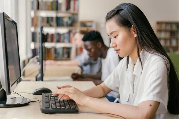 Young student using computer in a school library