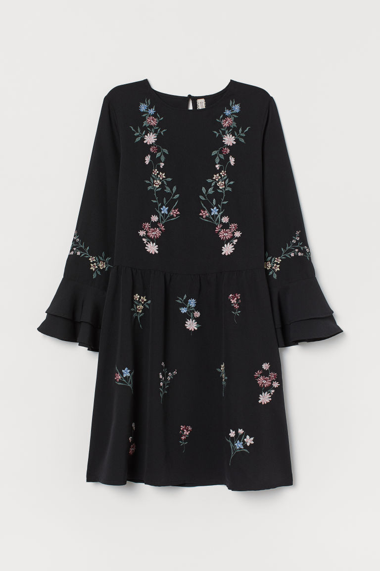 圓領短洋裝，縐紗平織布料，正面和衣袖有刺繡。領背有開口和單顆鈕扣，七分袖，雙層荷葉邊喇叭袖口。一側有隱形拉鍊，腰部有縫線，微傘狀裙襬。無內裡。