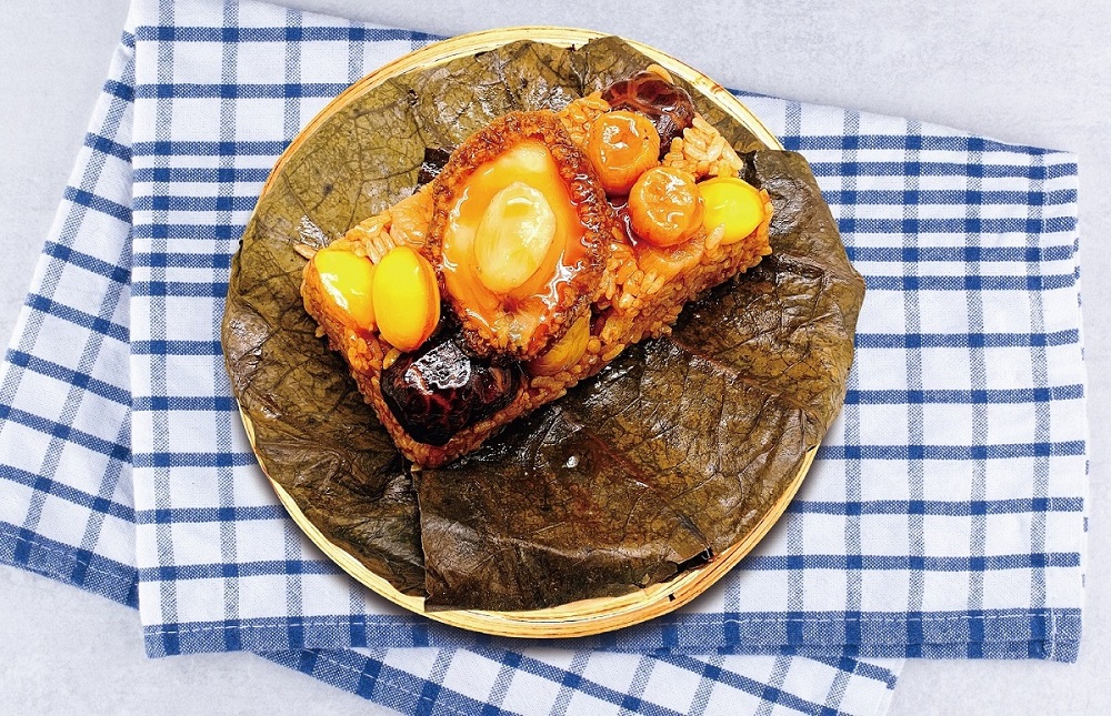 夢時代館內瓦城、饗泰多、開飯川食堂、品中信、Mia C'bon、黑橋牌…等餐飲品牌，紛紛推出特色端粽禮盒。圖為「鄧師傅」經典熱賣的「鮑魚干貝荷葉飯」。（圖片提供/高統一夢時代） 