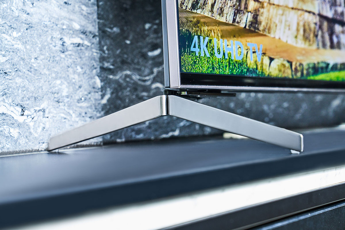 「平面纖薄設計」的一大重點就是可變換位置的可調整式底座，這樣的設計巧思能針對電視櫃的寬度彈性調整架設模式，上圖為腳座位於電視底部外側。