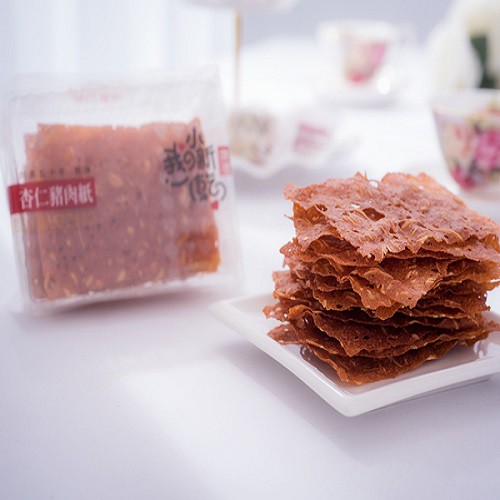 清香酥脆的杏仁脆片，絕對是點心時間的好選擇.嚴選現宰溫體台灣黑毛豬後腿裡僅有的鍵子肉(黃金十八兩)傳承50年的技術特調滷味醬汁每日現場烘烤將杏仁、嚴選豬肉充分混合後切成超薄片烤乾香脆的口感，讓您一口接