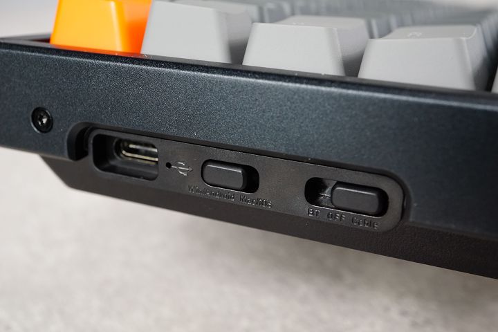 鍵盤側邊依序為充電孔、系統切換鍵、模式切換鍵，需依配對的裝置類型手動切換。