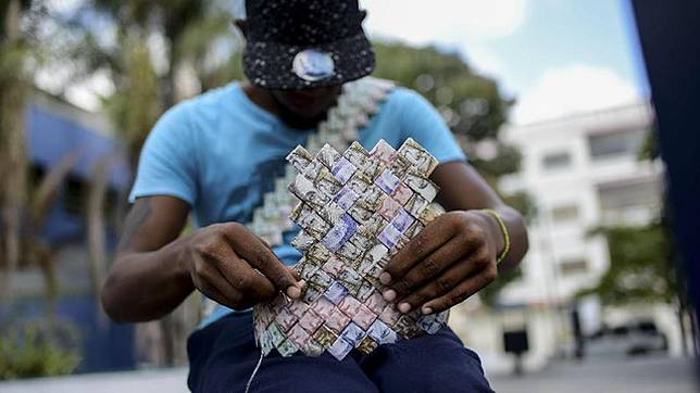 Wilmer Rojas (25) memungut uang kertas dari jalanan dan melipatnya dengan teknik serupa origami. (AFP Photo/Federico Parra)