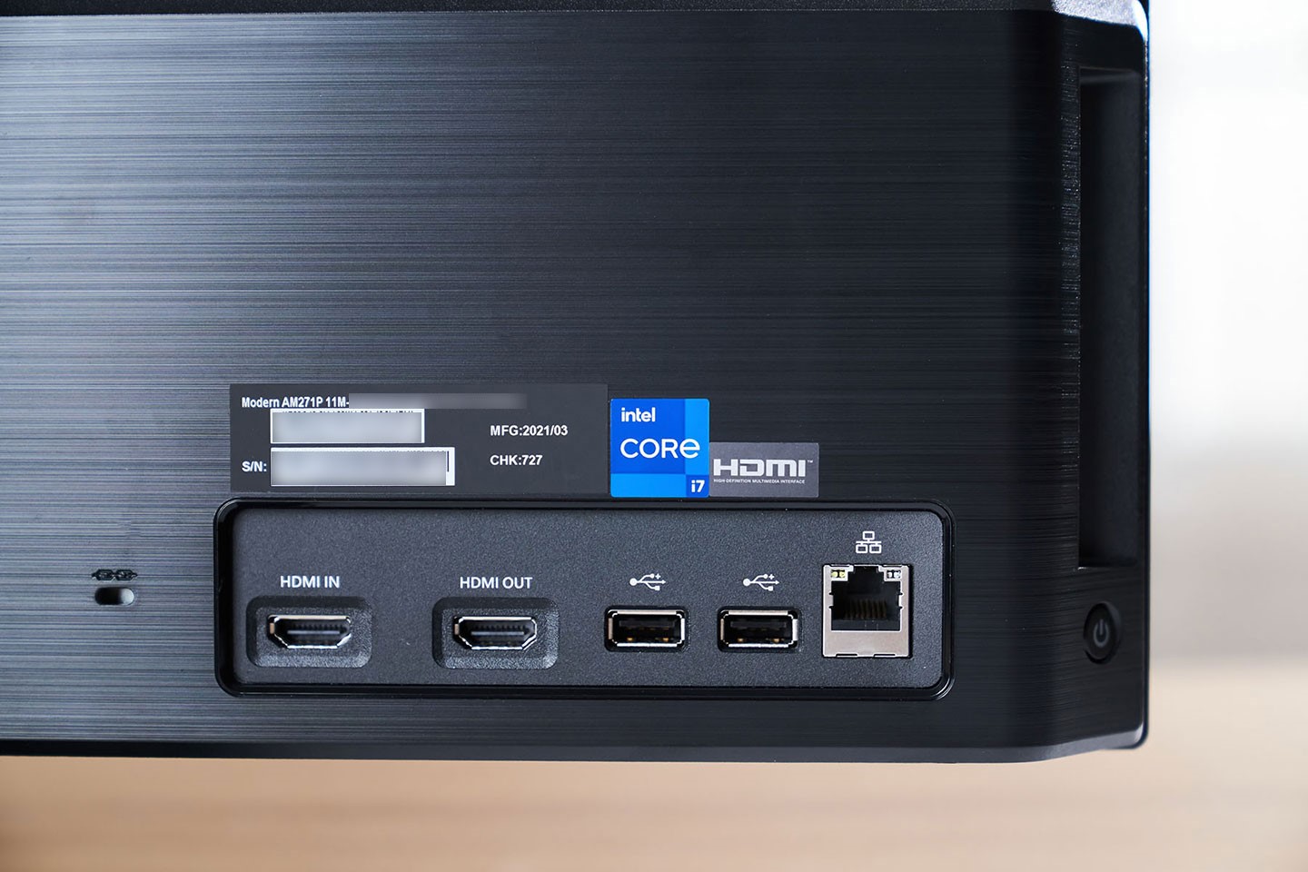 機身背面右下角配置了部份 I/O 埠、機身序號以及處理器識別貼紙，除了 RJ-45 網路孔與雙 USB 2.0 A 埠之外，Modern AM271 比較特別的就是同時配置了 HDMI OUT 與 HDMI IN 埠，不只可外接另一台螢幕組成雙屏模式，也能在電腦系統不使用時，作為一台單純的顯示器。