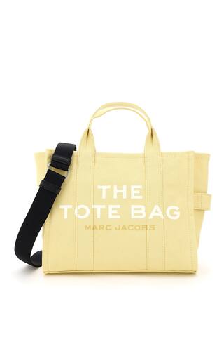 The Small Traveler Tote bag by Marc Jacobs in cotton canvas, featuring adjustable and removable webbing strap, front logo print, back logo patch, zip closure, side handle. Unlined interior with one zip pocket and two small pockets. Steel-finish metalware.