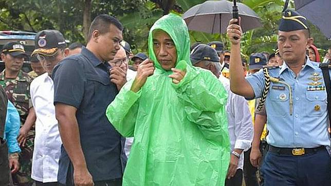Presiden Jokowi mengenakan jas hujan pemberian warga saat mengunjungi lokasi banjir dan longsor di Sukajaya, Bogor. twitter.com/setkabgoid