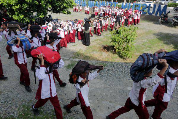 Pelajar melindungi kepala dengan tas saat mengikuti kompetisi simulasi evakuasi mandiri bencana gempa dan tsunami di Museum Tsunami