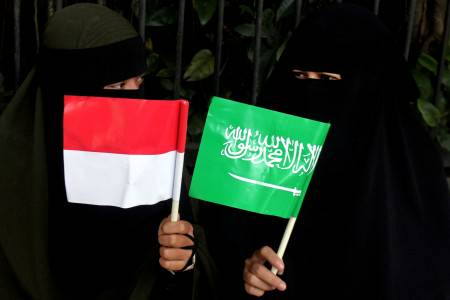 Dua orang warga memegang bendera untuk menyambut kedatangan Raja Salman di sekitar Istana Bogor, Kota Bogor, Jawa Barat, Rabu (1/3). Foto oleh Yulius Satria Wijaya/ANTARA