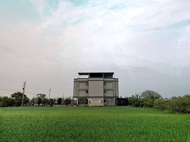 ▲矗立在田中的白貓民宿，遠遠便可看見牆面貓咪造型的燈飾。（圖/白貓民宿）