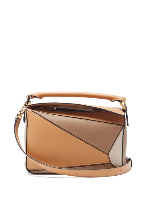 Loewe - Named by artisans for its complex 524-step assembly, Loewe's khaki-beige Puzzle cross-body bag is defined by its angular panels. It's crafted in the house's Spanish workshop from grained leather and features an Anagram-embossed flap top that opens to reveal a durable herringbone interior, then finished with lacquered edges for a graphic twist. Adjust the shoulder strap to carry it cross-body.