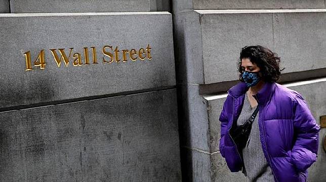 Seorang perempuan berjalan sambil mengenakan masker di sekitar Wall Street di New York, Amerika Serikat. Reuters