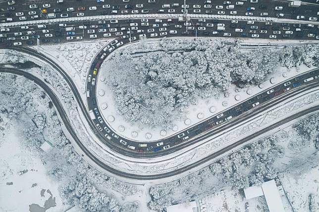 An aerial drone photo shows vehicles running on the road during snowy weather in Changsha, central China's Hunan Province, Jan. 22, 2024. (Xinhua/Chen Sihan)