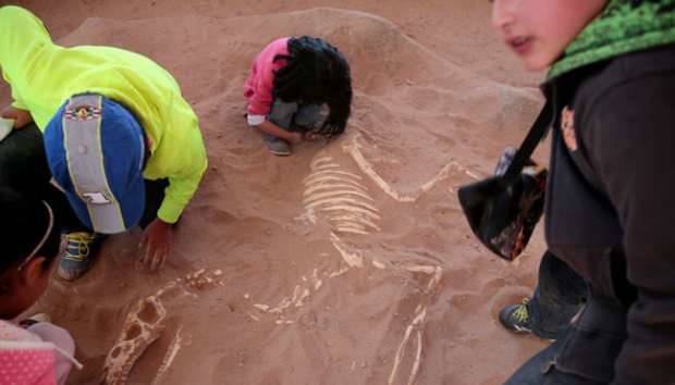 Sejumlah anak-anak bermain dengan sebuah fosil dinosaurus saat berada di taman Cretaceous, Cal Orcko, Bolivia, 22 Juli 2016. REUTERS/David Mercado